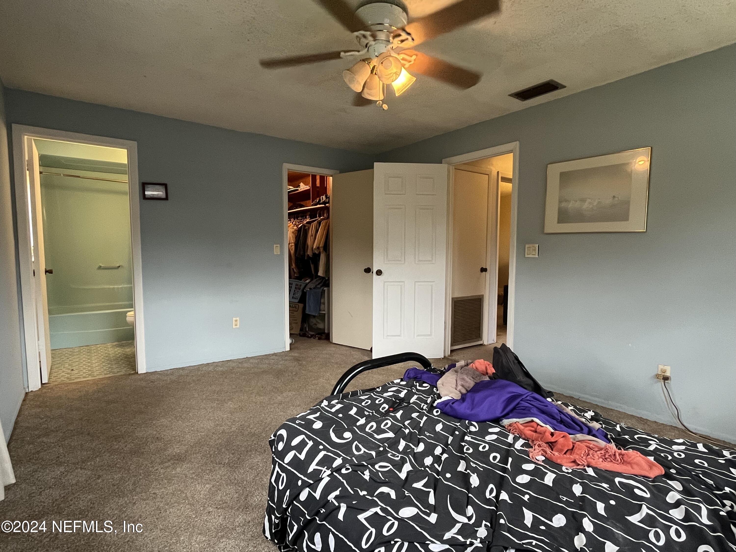 228 Lily Road St. Augustine, FL 32086 - Photo 23 of 34 a bedroom with a bed and a chandelier
