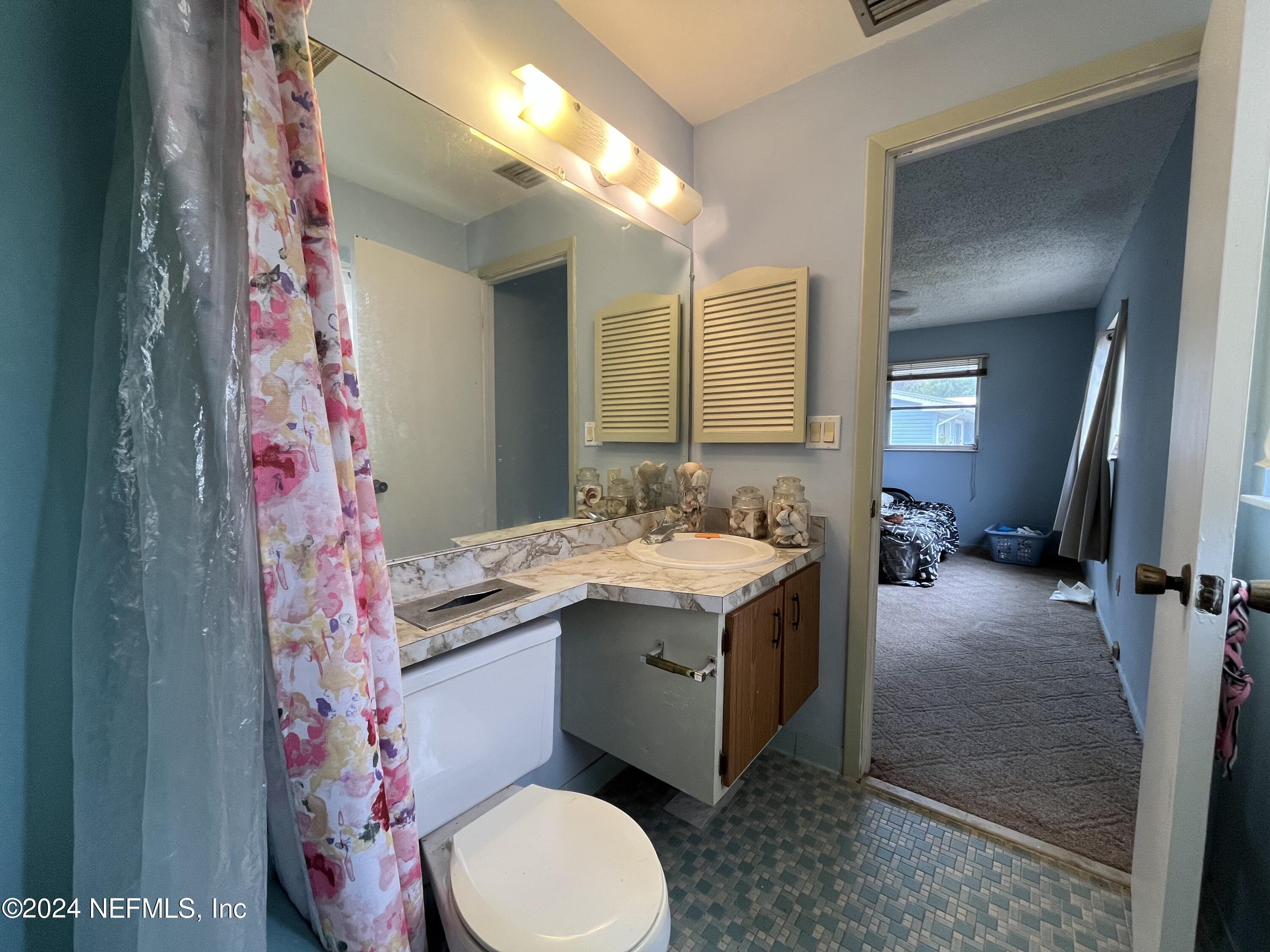 228 Lily Road St. Augustine, FL 32086 - Photo 25 of 34 a bathroom with a granite countertop sink mirror vanity and toilet