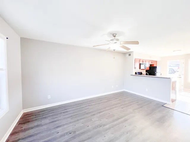 a view of a room with wooden floor and a ceiling fan