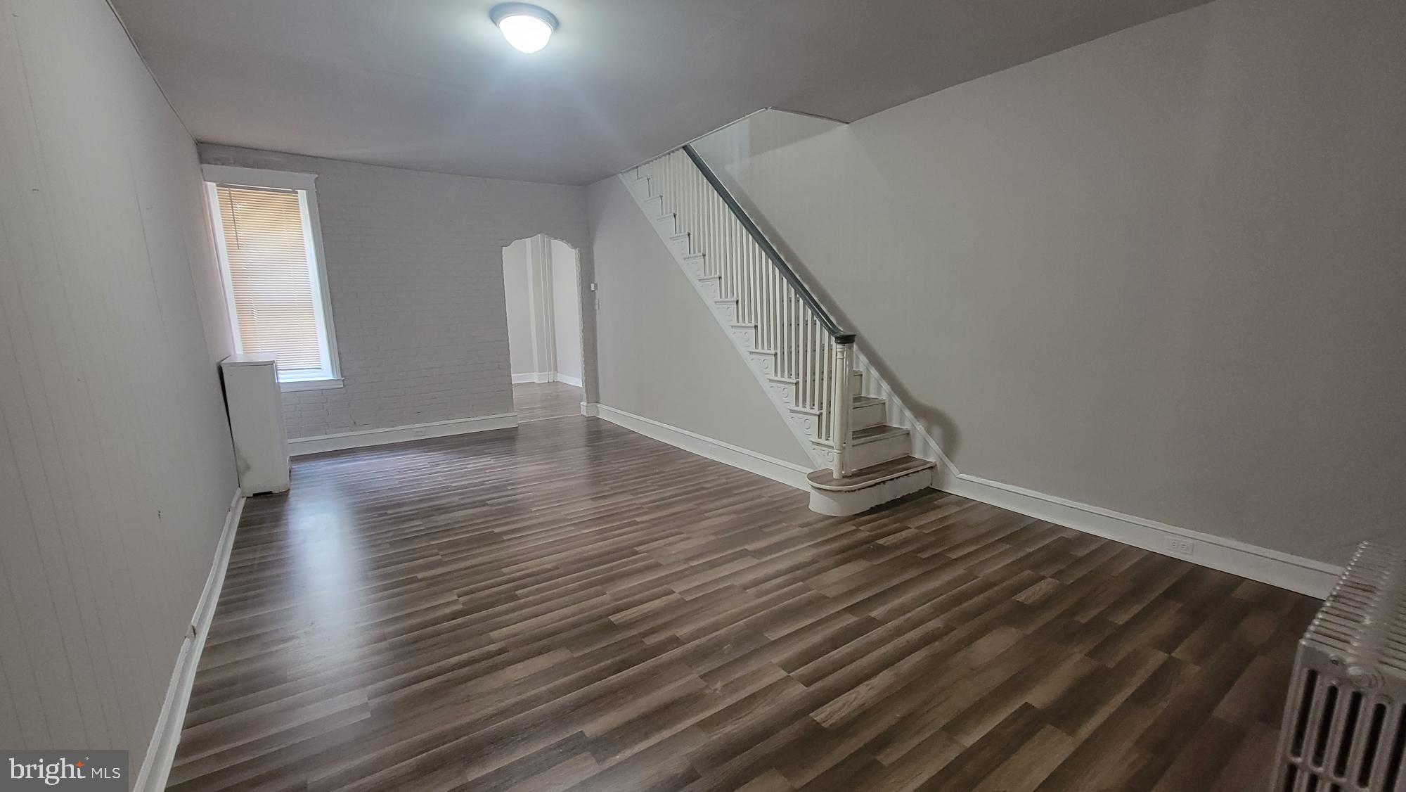 a view of an empty room with wooden floor and stairs