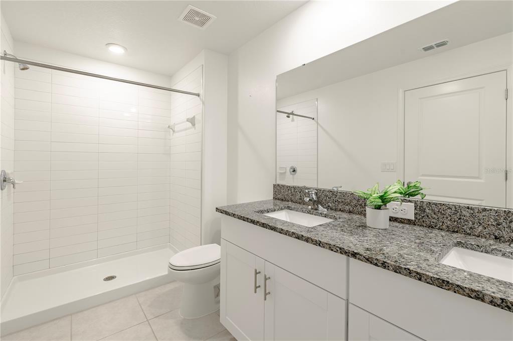 21395 Darter Road Land O' Lakes, FL 34638 - Photo 12 of 22 a bathroom with a granite countertop sink a toilet and shower