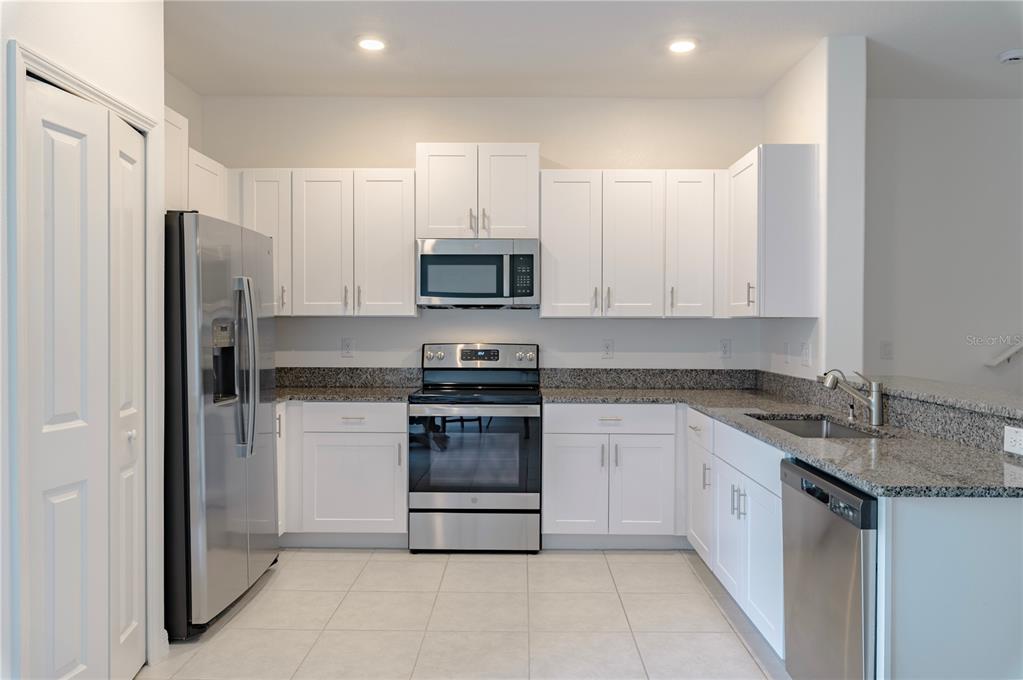 21395 Darter Road Land O' Lakes, FL 34638 - Photo 6 of 22 a kitchen with stainless steel appliances granite countertop a refrigerator and a stove top oven