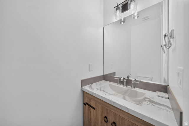 1002 West Temple Rim Lane Payson, UT 84651 - Photo 25 of 68 Bathroom vanity featuring a vessel sink, marble-finish countertop, brushed nickel faucet, and wood-finish cabinetry with dark hardware