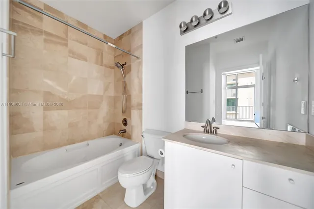 a bathroom with a granite countertop sink a toilet a mirror a bathtub and shower