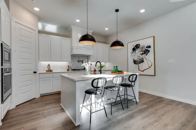 a kitchen with kitchen island stainless steel appliances a table chairs sink and wooden floor