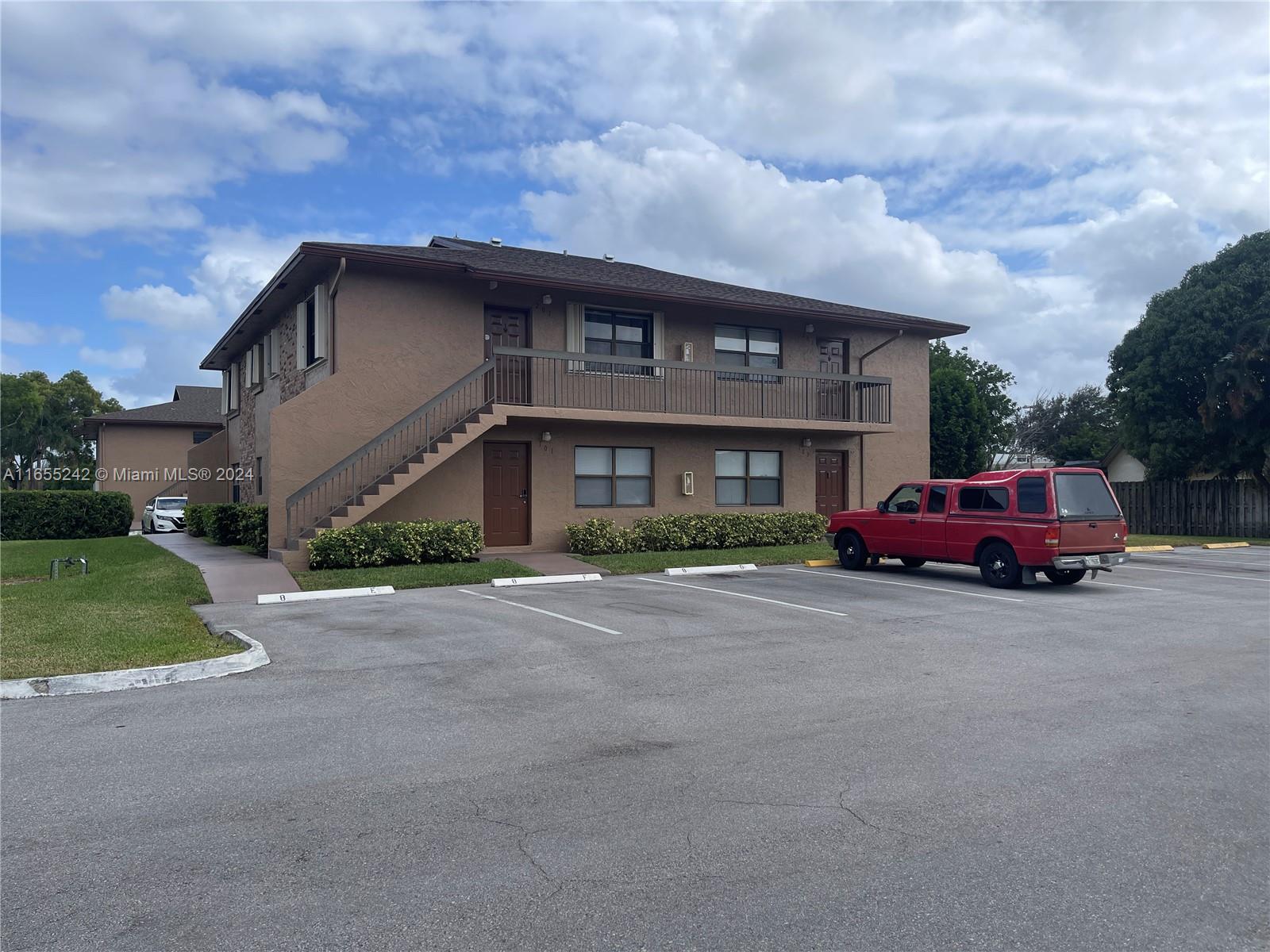 10057 Winding Lake Road, Unit 103 Sunrise, FL 33351 - Photo 2 of 13 a red car parked in front of a brick house