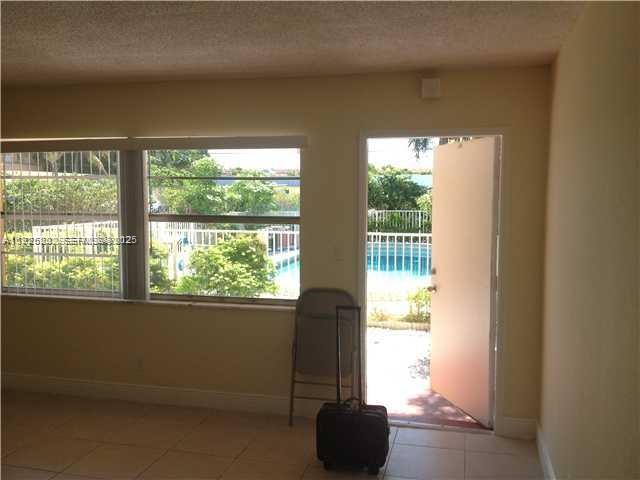 241 Southeast 9th Avenue, Unit 106 Pompano Beach, FL 33060 - Photo 7 of 19 a living room with a floor to ceiling window and a potted plant