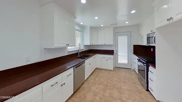 a kitchen with granite countertop white cabinets and black appliances