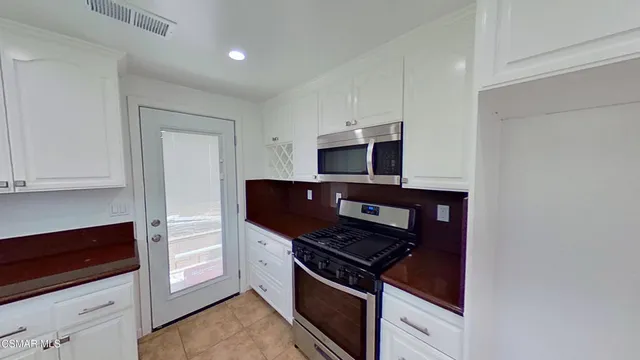 a kitchen with white cabinets and appliances