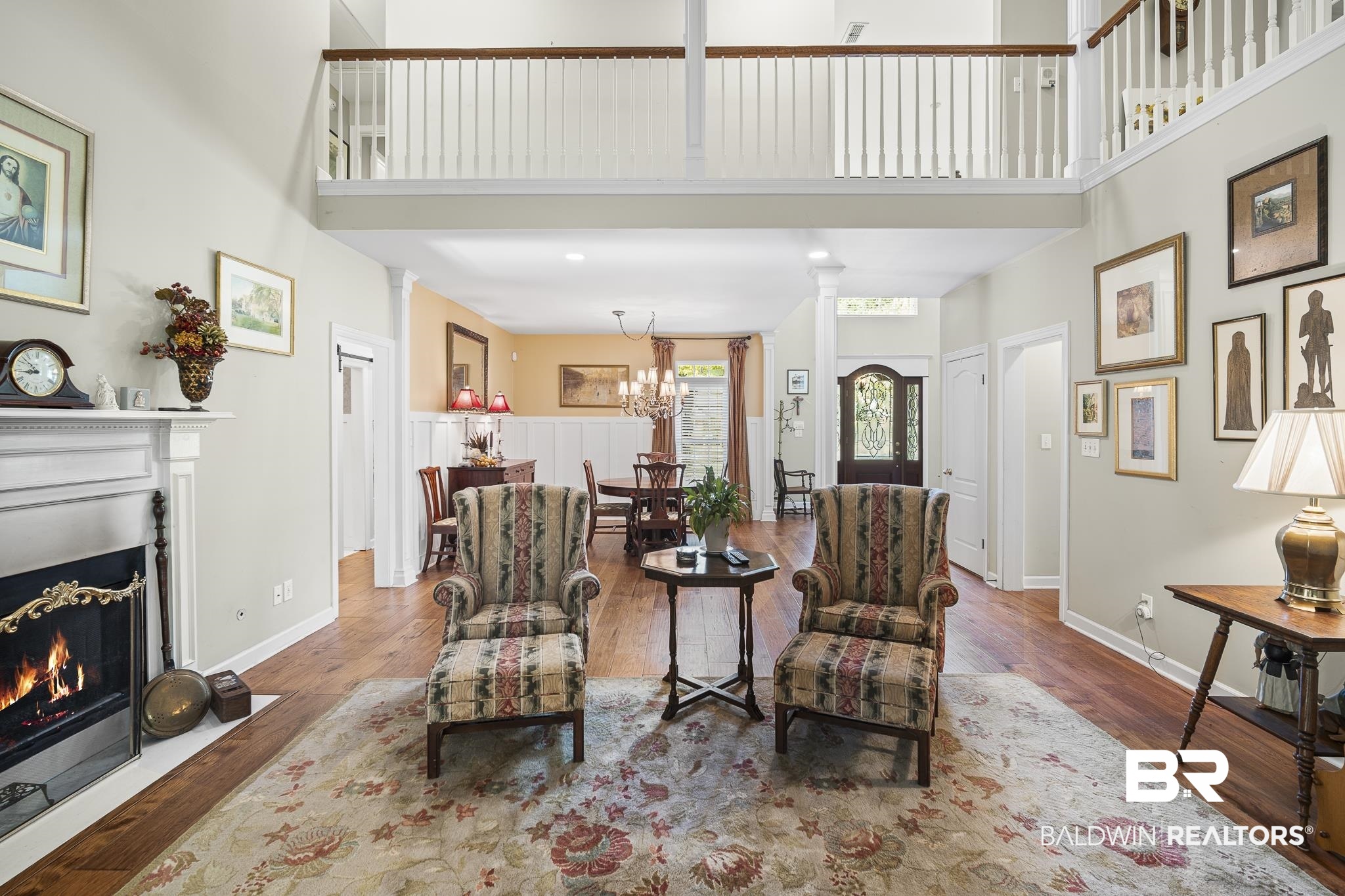 19876 Hunters Loop Fairhope, AL 36532 - Photo 8 of 40 Living area with a fireplace with flush hearth, a chandelier, wood finished floors, a high ceiling, and decorative columns