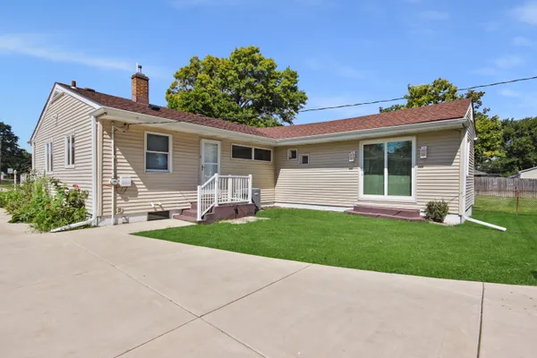 a view of a white house next to a yard with a large tree