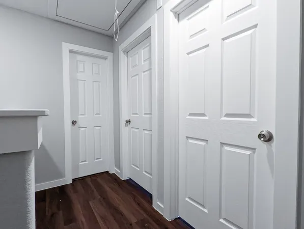 an empty room with wooden floor chandelier fan and windows