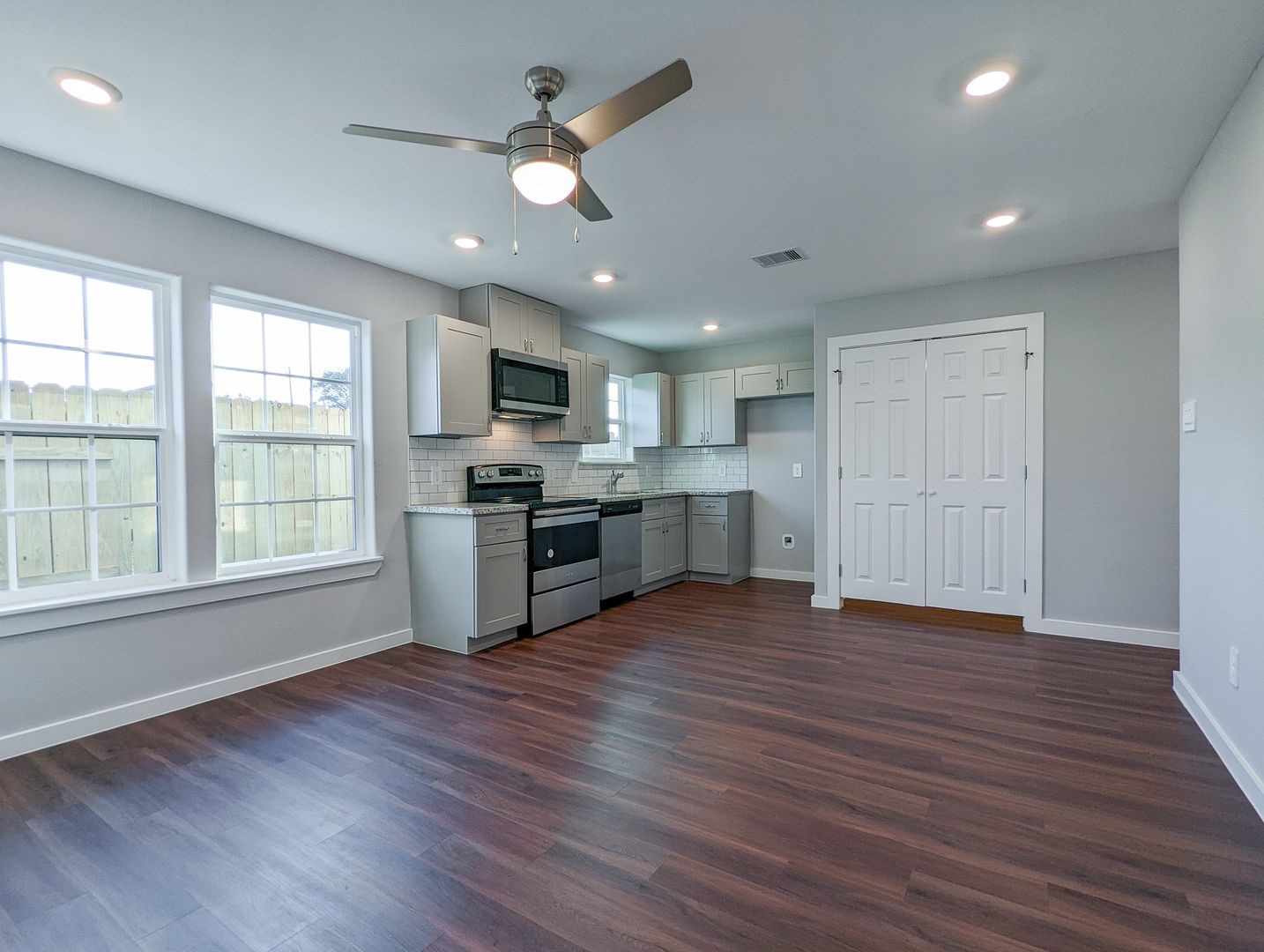 6811 Glass Street, Unit B Houston, TX 77016 - Photo 6 of 17 an empty room with wooden floor a ceiling fan and windows