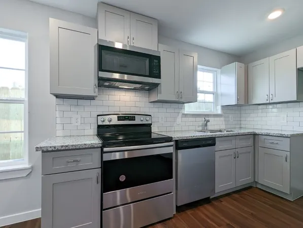 a view of a kitchen and an empty room with wooden floor