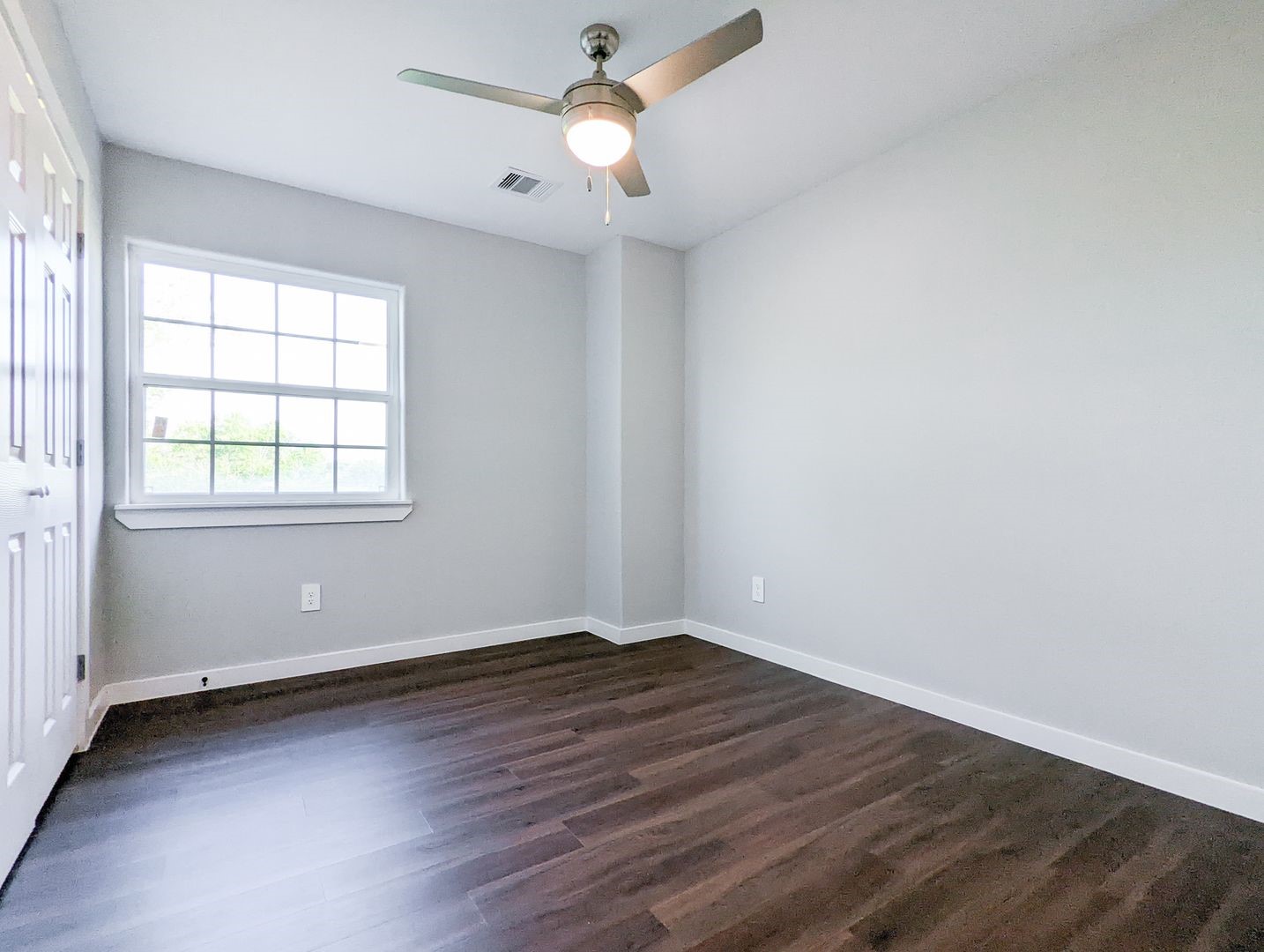 6811 Glass Street, Unit B Houston, TX 77016 - Photo 10 of 17 an empty room with wooden floor ceiling fan and windows