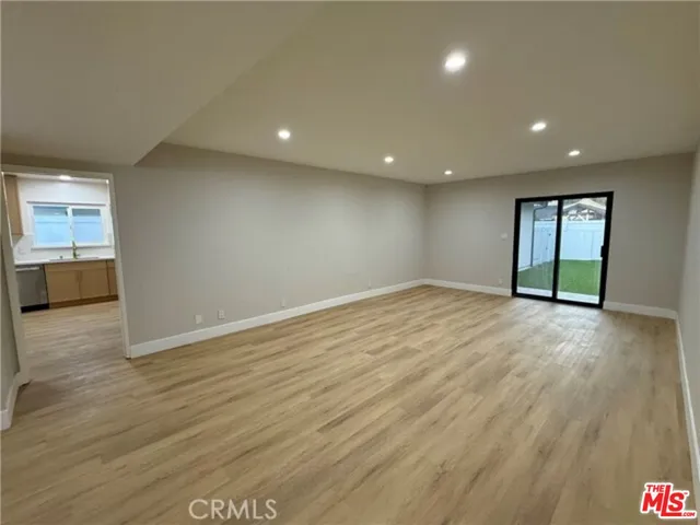 an empty room with wooden floor and natural light