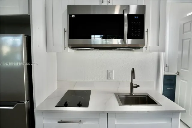 a kitchen with white cabinets and black appliances