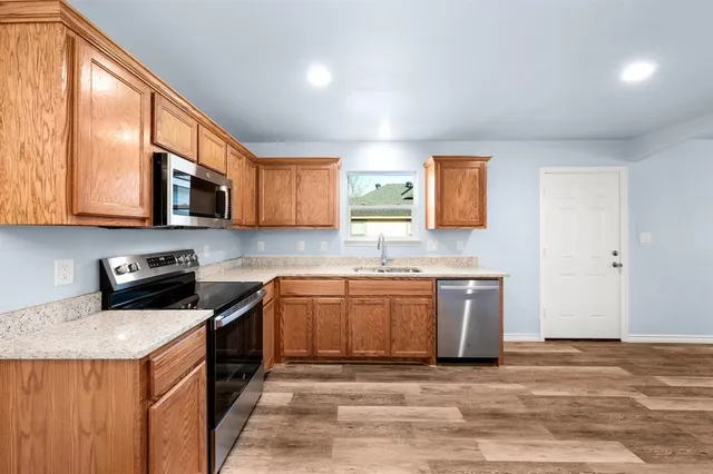 a kitchen with stainless steel appliances granite countertop a stove top oven a sink dishwasher and a microwave oven with white cabinets