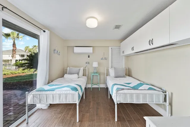 a bedroom with two beds and wooden floor