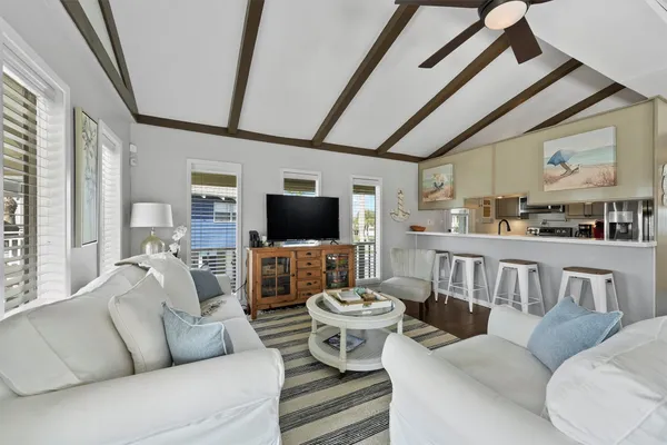 a living room with furniture a flat screen tv and kitchen view