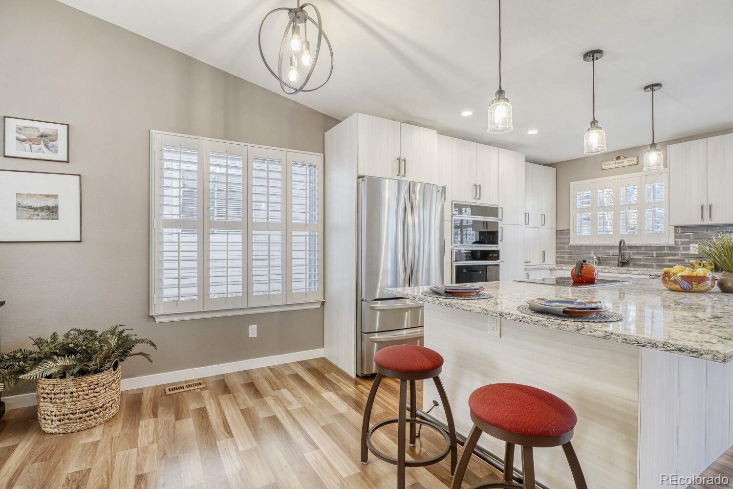 47 Canongate Lane Highlands Ranch, CO 80130 - Photo 12 of 22 a kitchen with stainless steel appliances kitchen island granite countertop a refrigerator a stove a sink dishwasher and white cabinets with wooden floor