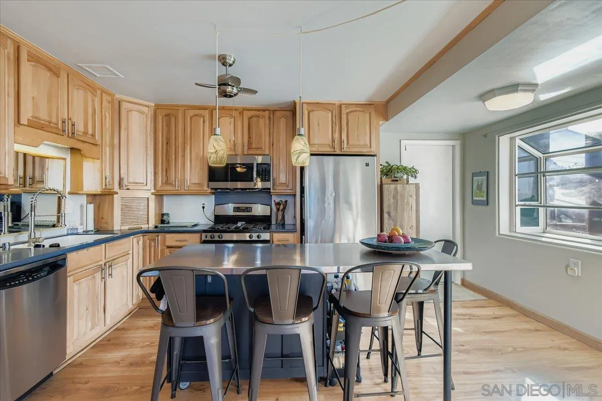 3275 East Virgo Road San Diego, CA 92105 - Photo 1 of 38 a kitchen with stainless steel appliances granite countertop a dining table chairs refrigerator a sink and dishwasher
