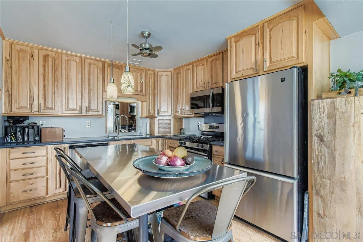 3275 East Virgo Road San Diego, CA 92105 - Photo 8 of 38 a kitchen with stainless steel appliances granite countertop a dining table and chairs