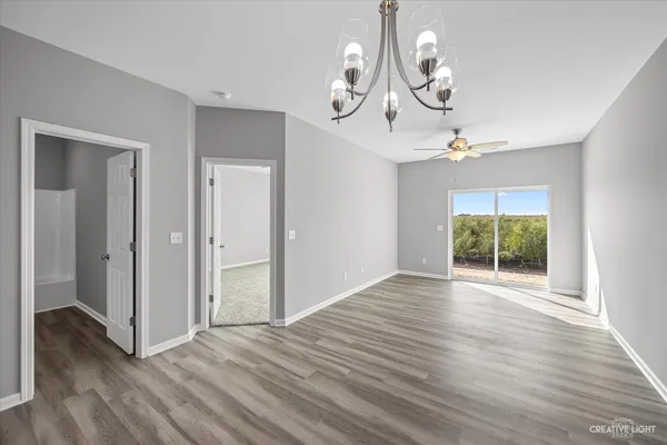 an empty room with wooden floor mirror and windows