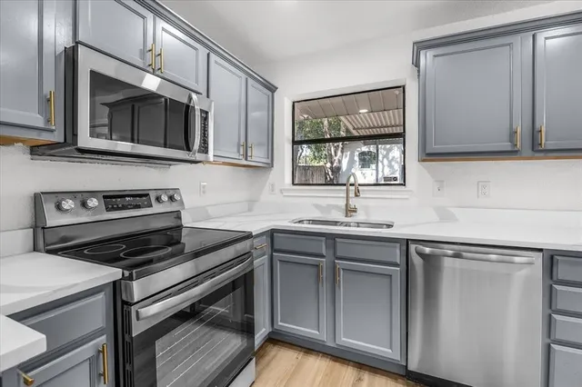 a kitchen with stainless steel appliances a stove microwave and sink