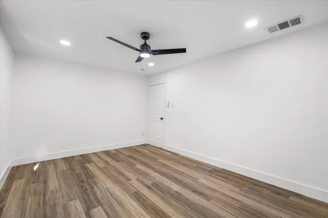 an empty room with a hardwood and ceiling fan