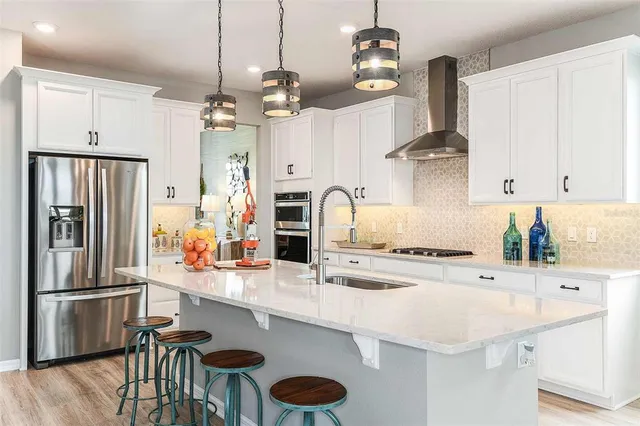 a kitchen with stainless steel appliances granite countertop a sink a stove and a refrigerator