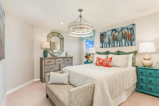 a bedroom with a bed a chandelier and dresser