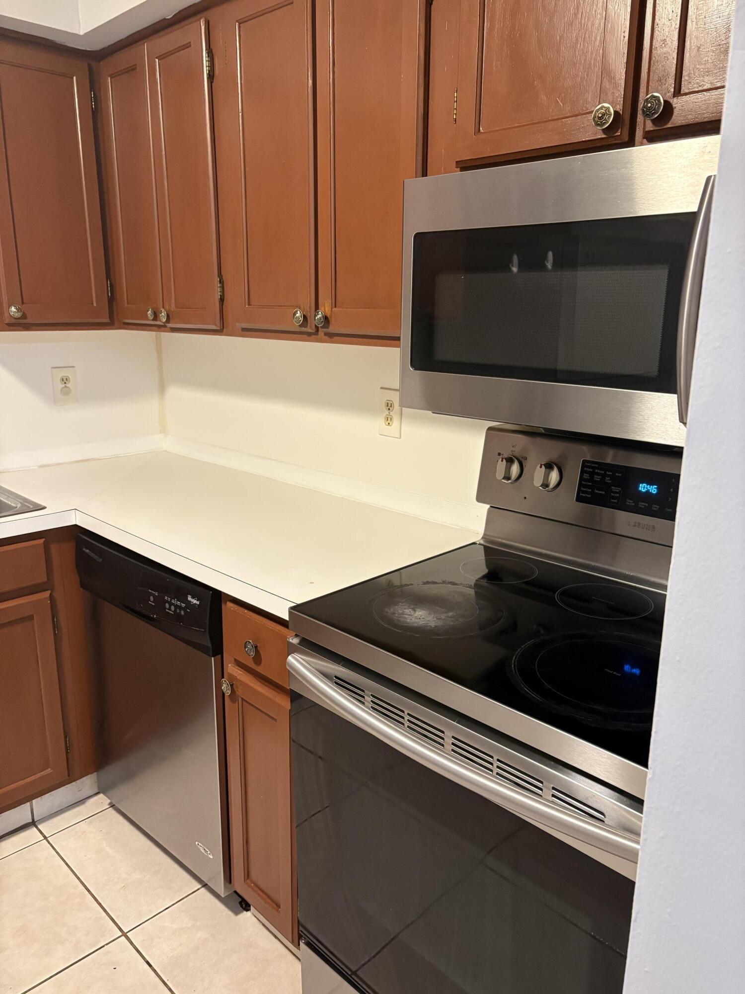 9845 Pineapple Tree Drive, Unit 208 Boynton Beach, FL 33436 - Photo 11 of 21 a kitchen with granite countertop white cabinets and black appliances