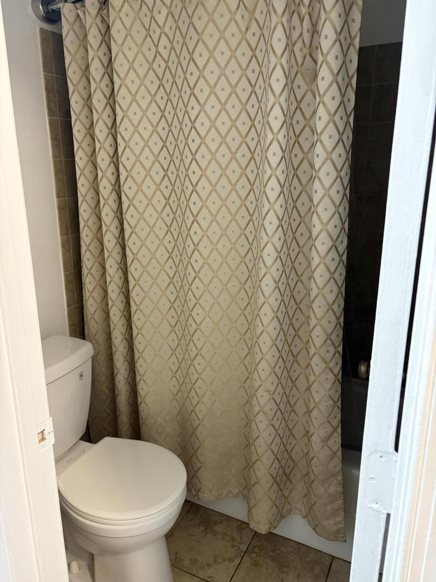 9845 Pineapple Tree Drive, Unit 208 Boynton Beach, FL 33436 - Photo 9 of 21 a white toilet sitting next to a shower curtain