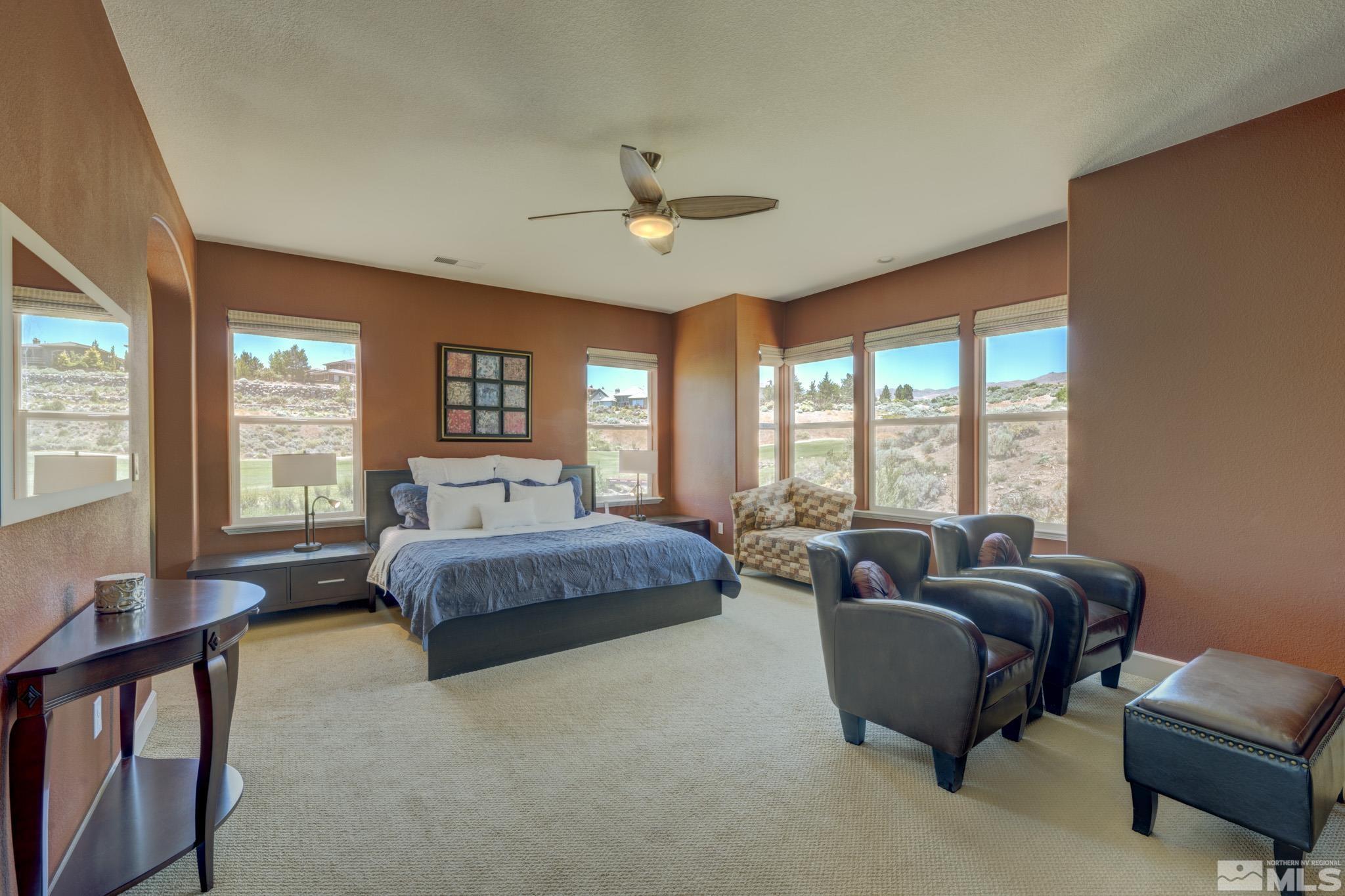 8490 Castlehawk Court Reno, NV 89523 - Photo 23 of 40 a spacious bedroom with a bed a couch and large windows