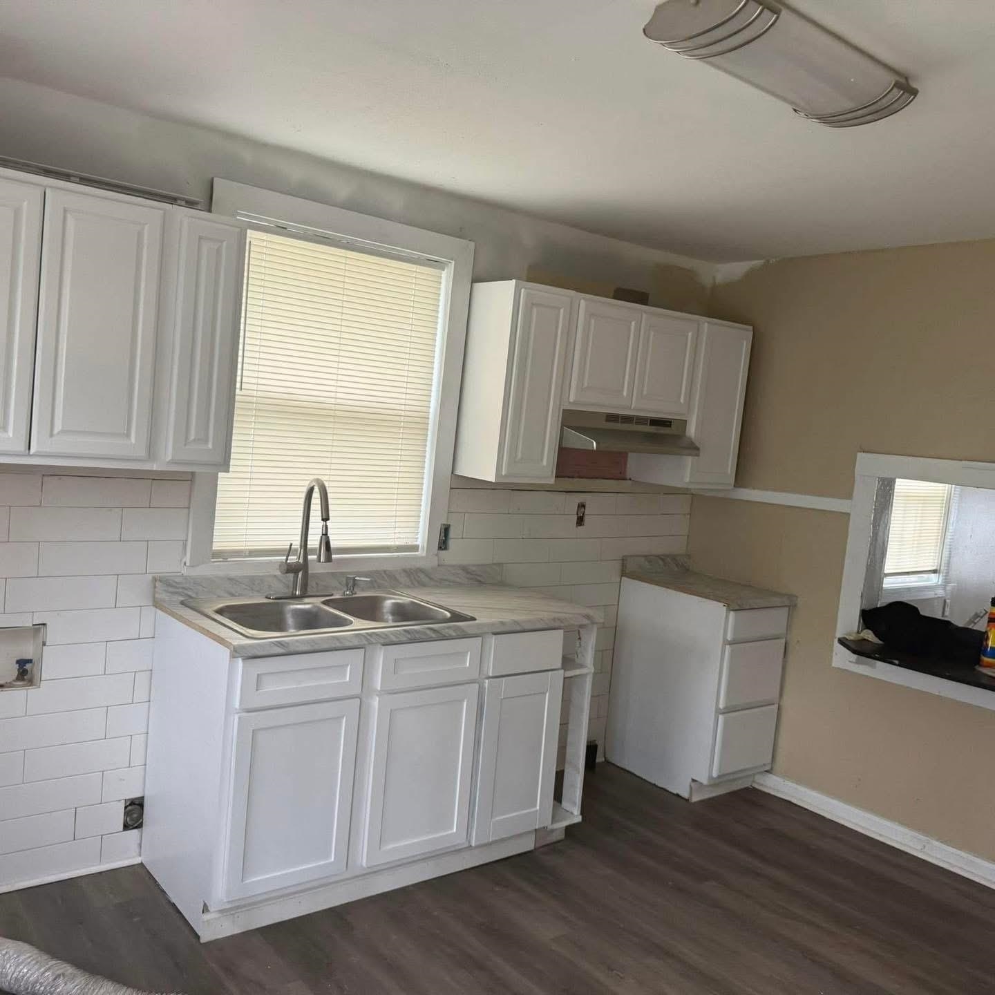 3596 Kendrick Road Memphis, TN 38108 - Photo 2 of 9 Kitchen featuring white cabinets, light countertops, dark wood-style floors, and under cabinet range hood