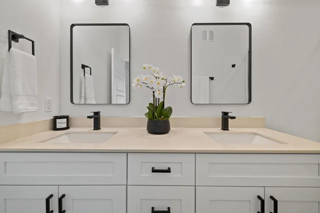 a bathroom with double vanity sinks and two mirror