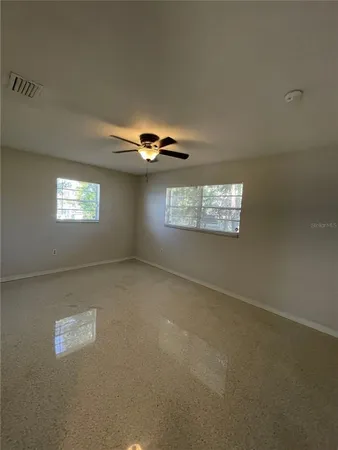 an empty room with windows and chandelier fan