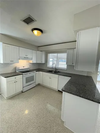 a kitchen with granite countertop a refrigerator and a sink