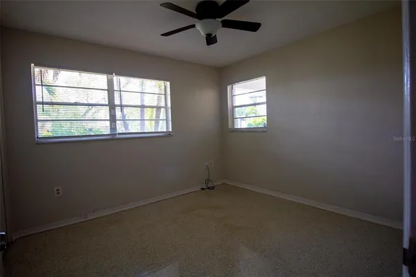 an empty room with windows and ceiling fan
