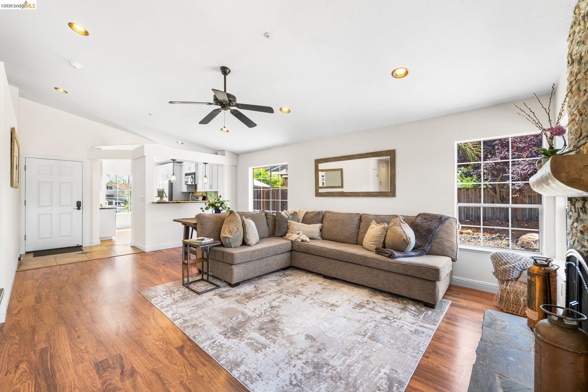 1186 El Rio Court Livermore, CA 94551 - Photo 7 of 60 Spacious living area featuring wood-finish flooring, a stone fireplace with a substantial mantel, and multiple windows