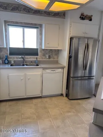 a kitchen with stainless steel appliances granite countertop a refrigerator a sink a stove with white cabinets