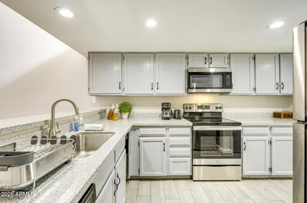 a kitchen with granite countertop a stove top oven sink and cabinets