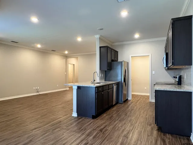 a kitchen with stainless steel appliances granite countertop a stove a sink dishwasher a refrigerator and a oven with wooden floor