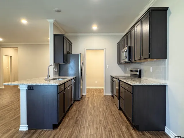 a large kitchen with stainless steel appliances granite countertop a stove refrigerator and a sink