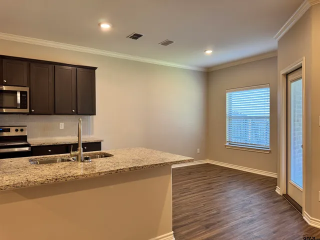 a kitchen with granite countertop sink cabinets and wooden floor