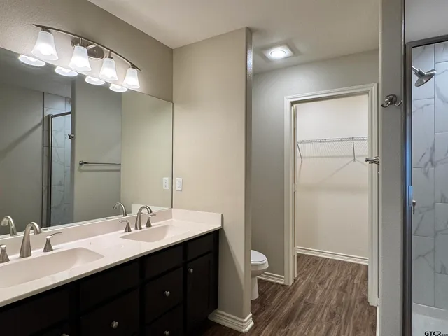a bathroom with a double vanity sink a toilet and a mirror
