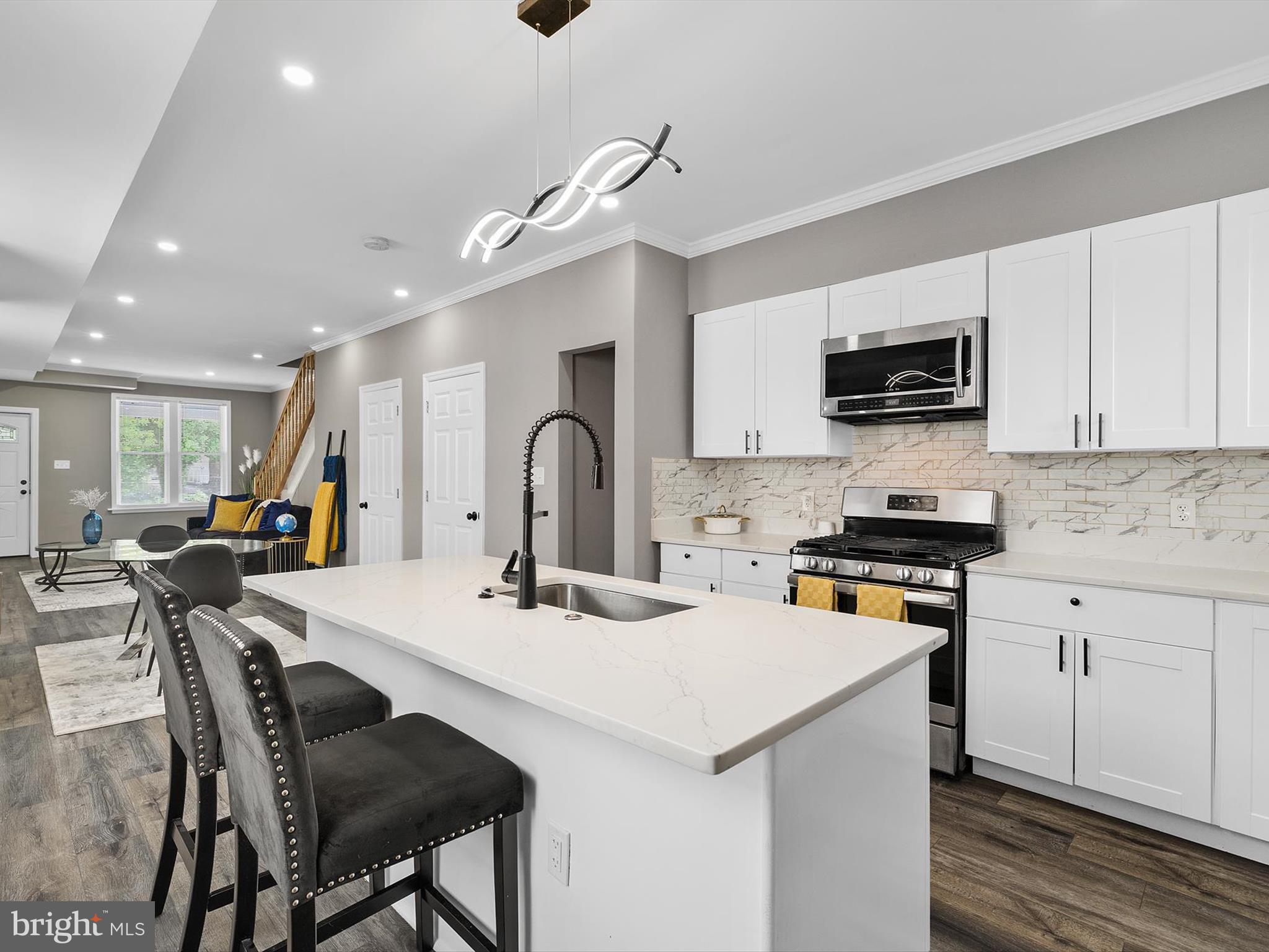 3032 Chelsea Terrace Baltimore, MD 21216 - Photo 11 of 29 a kitchen with stainless steel appliances kitchen island granite countertop a stove a sink a dining table and chairs with wooden floor