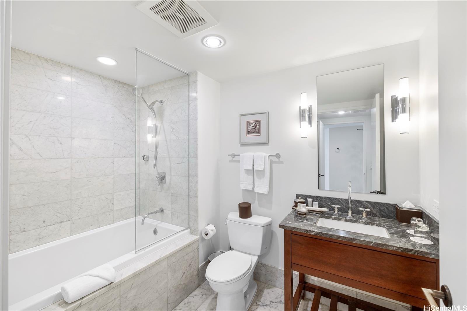 223 Saratoga Road, Unit 3203 Honolulu, HI 96815 - Photo 24 of 24 a bathroom with a granite countertop sink a toilet a mirror and a bathtub