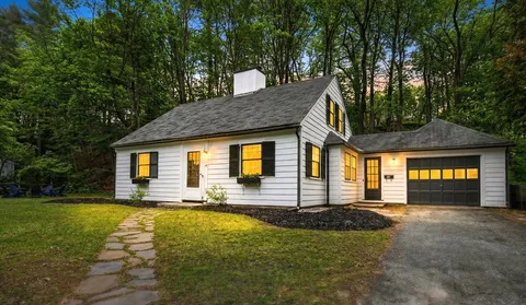 a front view of house with yard and trees in the background